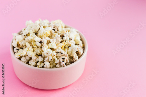 Popcorn in a pink bowl on pink background close-up