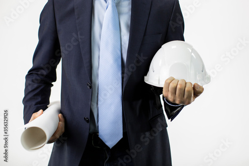 Close up engineer in formal suit holds hard safety helmet hat and blueprint roll isolated on white background. Architector, industrial sphere, heavy petrochemical industry photo