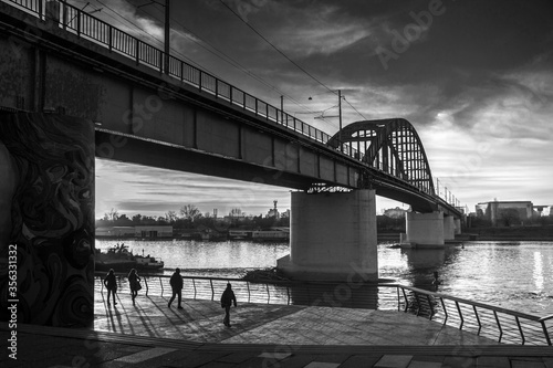 Belgrade, Serbia - Walkers at the riverside promenade under the tram bridge spanning the Sava River