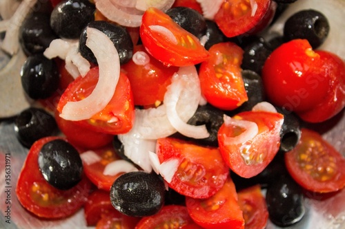 closeup of tomato, onions and black olives salad washed and cut ready to be eaten 