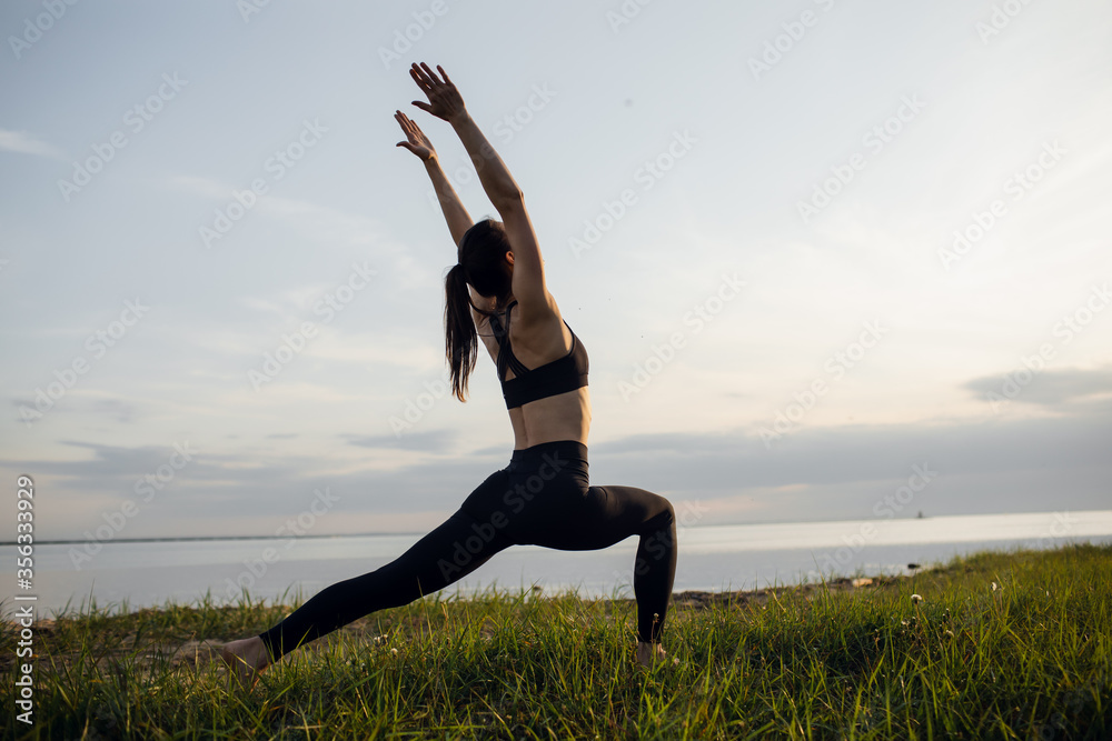 young athletic girl is engaged in yoga warrior pose outdoor young athletic girl is engaged in yoga warrior pose outdoor