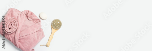Female pink bathrobe, massage brush, soap on a white background. Copy space, flat lay. Banner