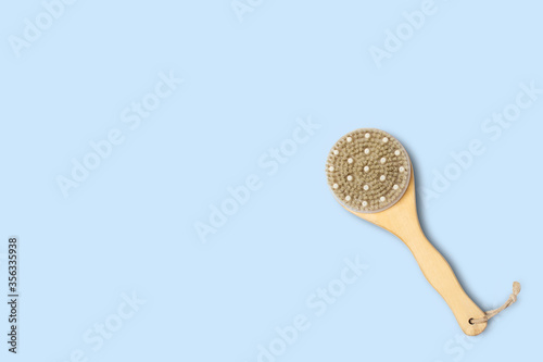 Dry massage brush on a blue background. Natural bristles. Copy space, flat lay