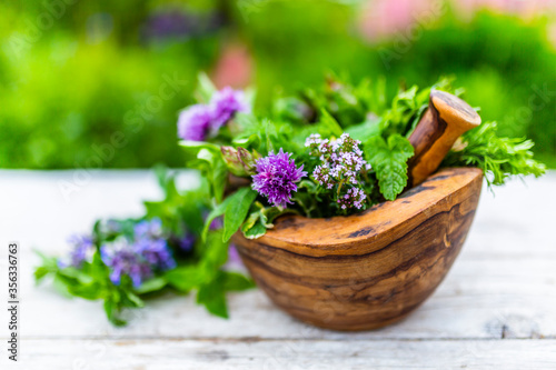 Fresh and aromatic herbs in a wooden mortar.