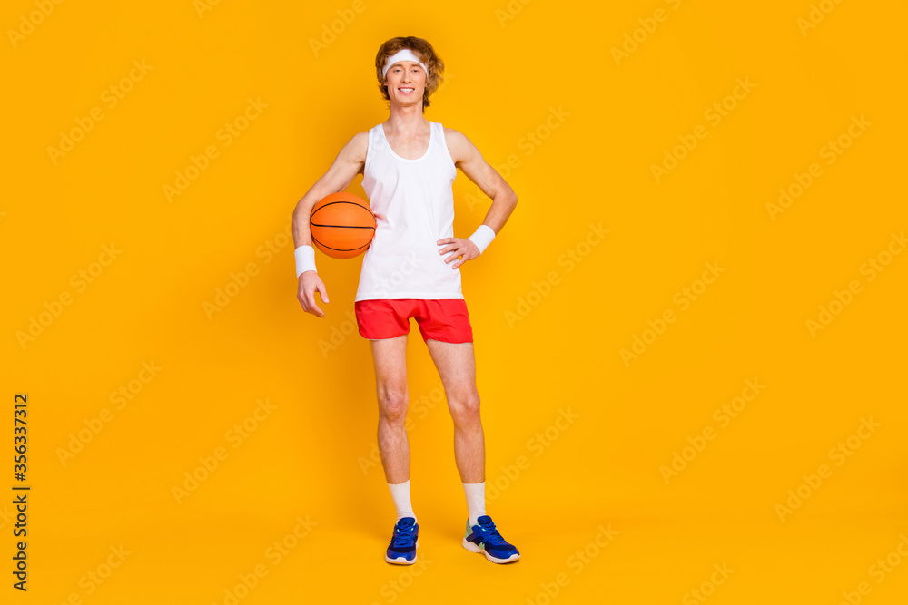 Full length body size view of his he nice attractive cheerful cheery content successful guy sportsman holding in hand orange ball isolated over bright vivid shine vibrant yellow color background Full length body size view of his he nice attractive cheerful cheery content successful guy sportsman holding in hand orange ball isolated over bright vivid shine vibrant yellow color background