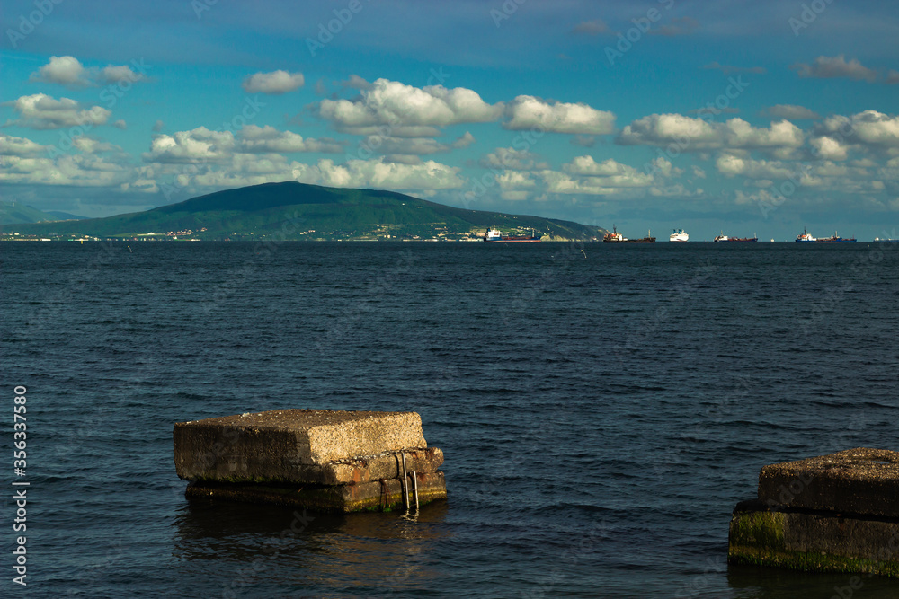 The remains of the old pier and a view of the exit from the sea bay with ships