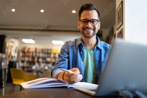 Smiling male student working and studying in a library