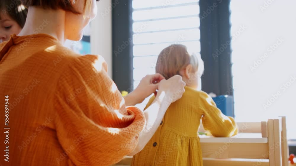 Mother with small children in bedroom in the morning at home, getting dressed.