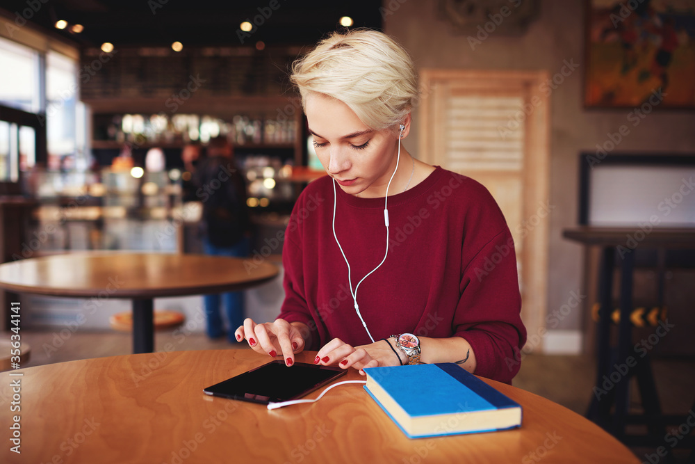 Caucasian millennial female teenager using tablet in coffee shop Caucasian millennial female teenager using tablet in coffee shop