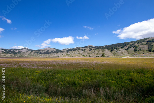 Mountain landscape of the Italian Apennines. Flowery field in spring. Plateau Rascino with flowering and greenery. Italian mountain panorama. Real picture