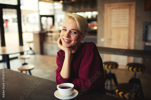 Caucasian young female enjoying cappuccino drink in coffee shop