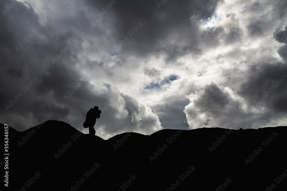 Silhouette of a man in the mountains is taking pictures of the landscape
