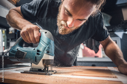 Man using a jigsaw on a wooden countertop  photo