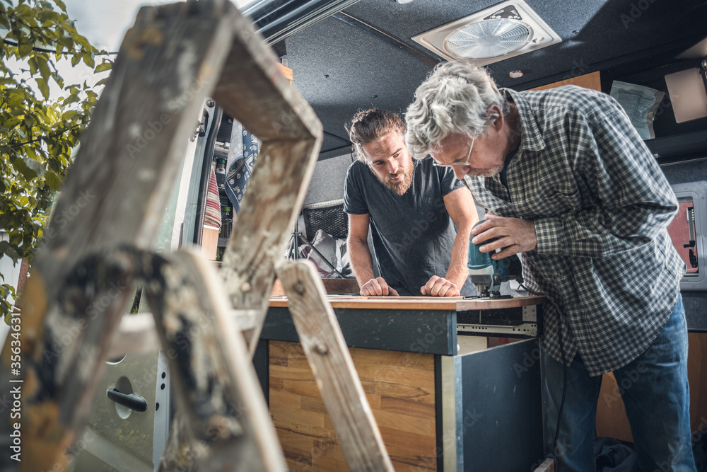 Fototapeta premium Father and adult son working on a caravan