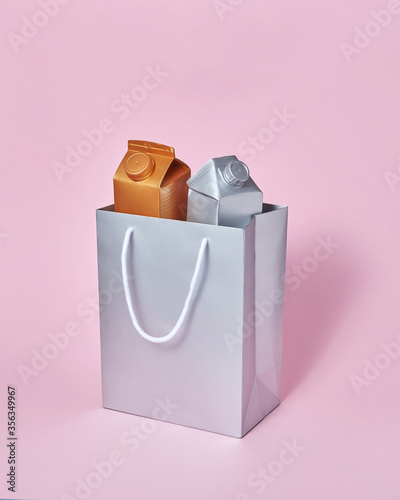Mock-up silver paper bag with two milk packages on a pink background. photo