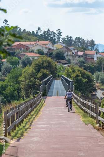 Eco view pedestrian / cycle lane, with senior man cycling and pedaling, wooden barrier on edges