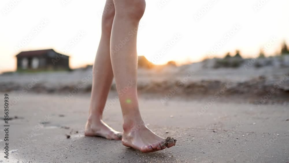 Slim female legs and feet walking along sea water waves on sandy beach. Pretty woman walks at seaside surf. Splashes of water and foam in 120 fps slow motion. Girl after bathing in ocean go on shore. Slim female legs and feet walking along sea water waves on sandy beach. Pretty woman walks at seaside surf. Splashes of water and foam in 120 fps slow motion. Girl after bathing in ocean go on shore.