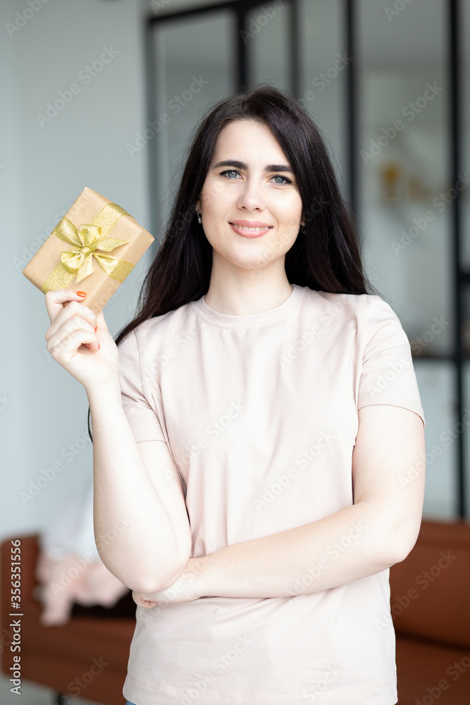 Portrait of happy smiling woman holding golden gift box. Celebrating concept. Portrait of happy smiling woman holding golden gift box. Celebrating concept.