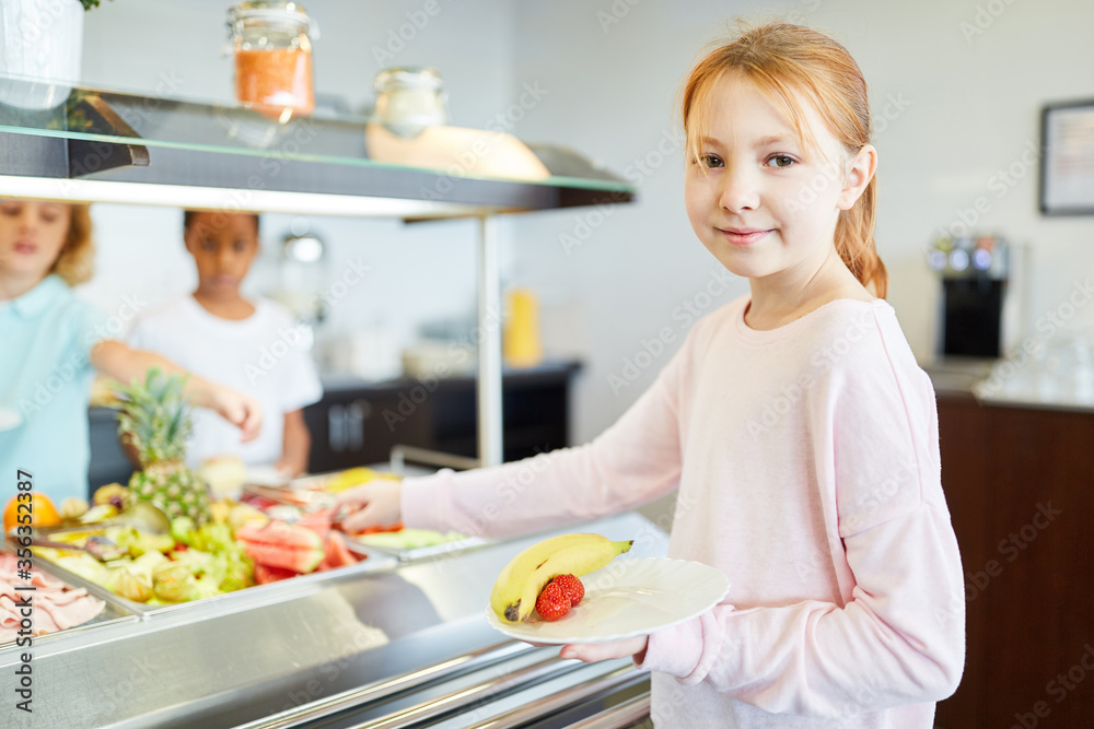 Mädchen holt sich Obst am Büffet