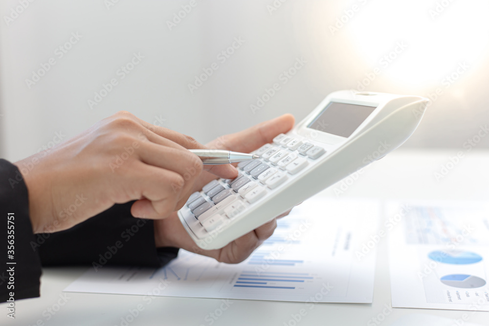 Businesswomen are calculating finances and analyzing market data with graphs and laptops at work, Business Financing Accounting Banking and tax system Concept. Businesswomen are calculating finances and analyzing market data with graphs and laptops at work, Business Financing Accounting Banking and tax system Concept.