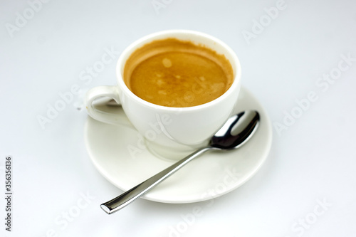 coffee on a white plate with a spoon on a white background
