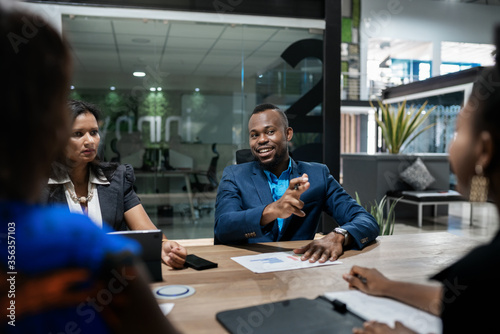 Smiling young African businessman talking with colleagues during an office meeting