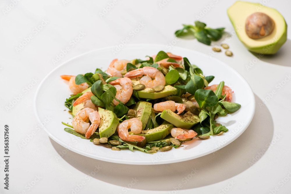 selective focus of fresh green salad with shrimps and avocado on plate on white background selective focus of fresh green salad with shrimps and avocado on plate on white background