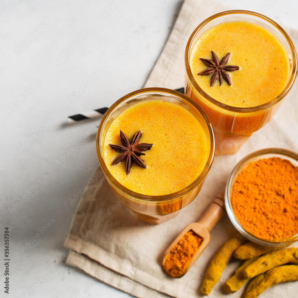 Turmeric smoothie in glass with ingredients, powder, ginger and spice on white Turmeric smoothie in glass with ingredients, powder, ginger and spice on white