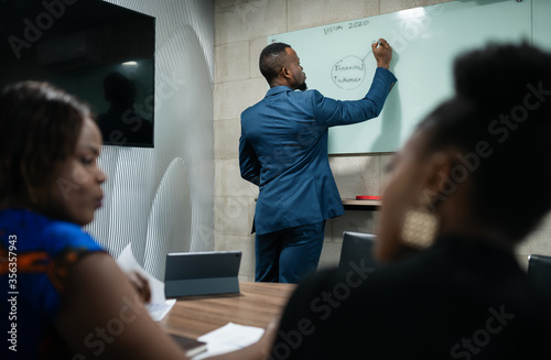 African manager doing a whiteboard presentation during an office presentation photo