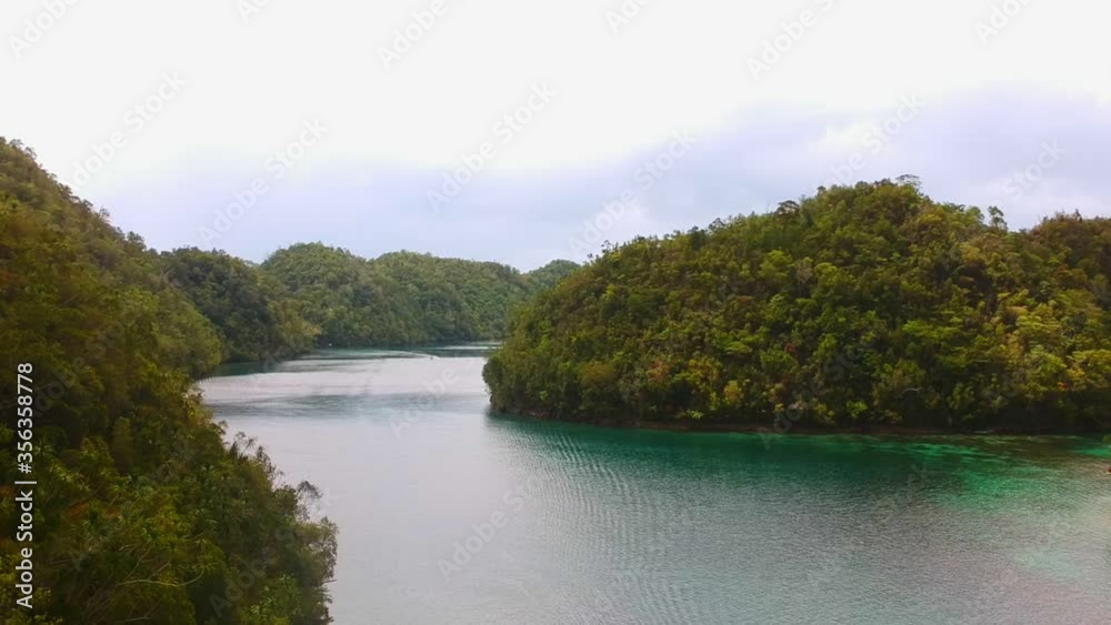 Drone shot of a colorful lagoon amidst many forested hills in Siargao Drone shot of a colorful lagoon amidst many forested hills in Siargao
