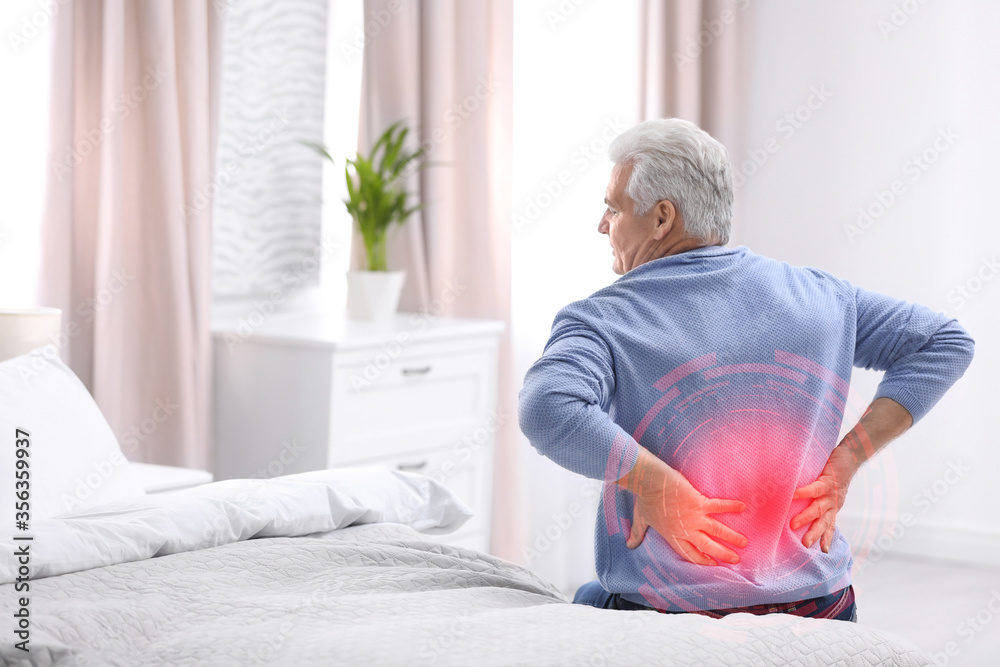 Senior man suffering from back pain after sleeping on