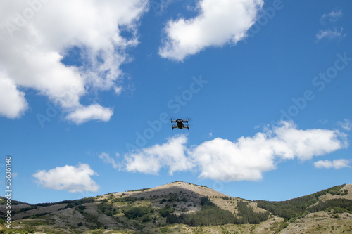 Drone in flight hovering in a flowery field in the spring in the mountains. Aerial shots and selfies with the drone. Control and agriculture with drone.
