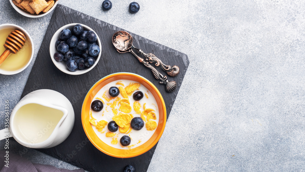 Corn flakes made from natural cereals with fresh blueberries, honey and milk. The concept of a healthy wholesome Breakfast. copy space Grey concrete background