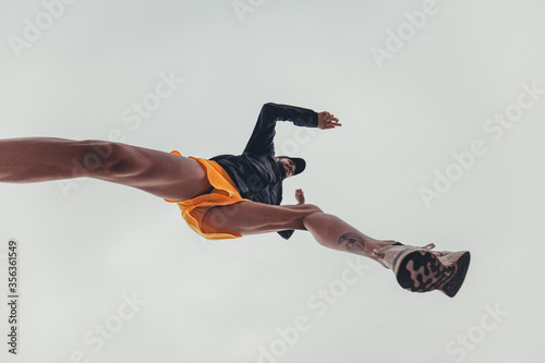 ragazzo atletico si allena saltando in aria con forza e determinazione durante una sessione di allenamento urbano
