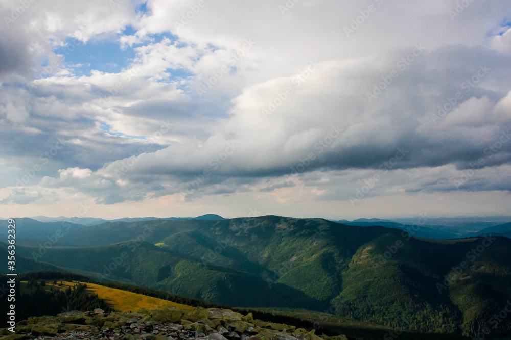 Fototapeta premium Beautiful view of the mountains from above, the rays of the sun make its way through the clouds, bright sky, evening