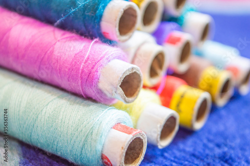 Multi coloured thread rolls stacked at a workplace for sewing.