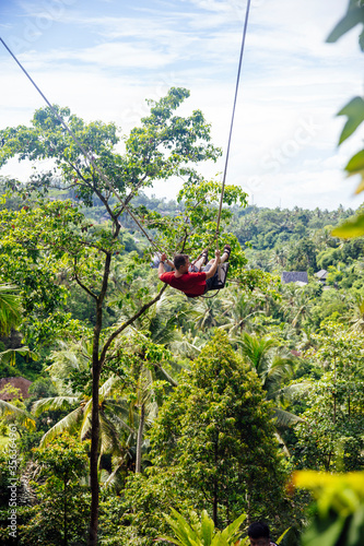 Young male tourist swinging on the cliff in the jungle