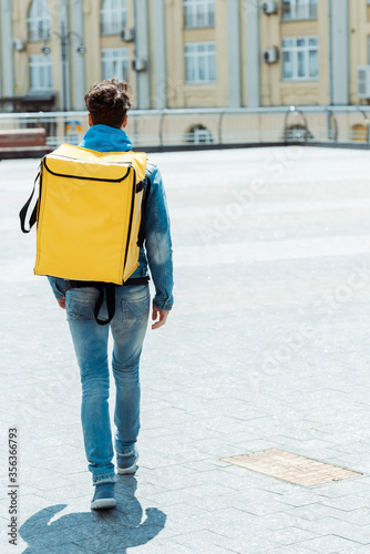 Back view of delivery man carrying thermo backpack on urban street © LIGHTFIELD STUDIOS