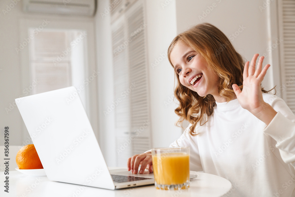 Photo of cheerful girl taking video call on laptop and waving hand Photo of cheerful girl taking video call on laptop and waving hand