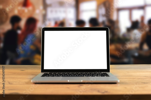 Mockup blank screen laptop on wood table in co-working space. Coffee Restaurant