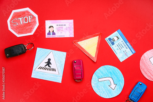 Driving license with car keys and road signs on color background