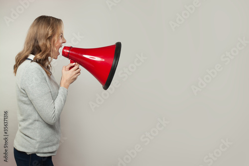 Real woman screaming with loudspeaker megaphone. Girl holding red bullhorn