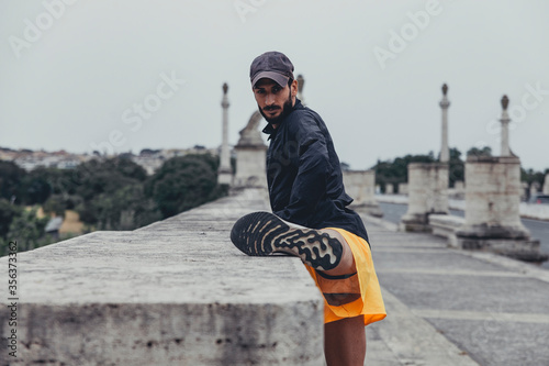 Giovane atleta esegue un esercizio di allungamento delle gambe con concentrazione durante una sessione di allenamento solitario in città