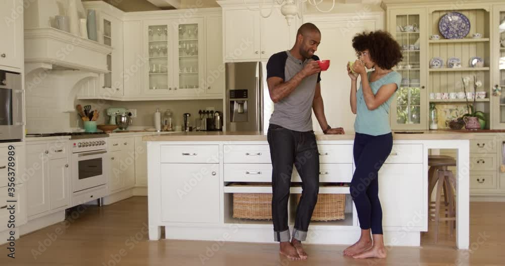 Happy mixed race couple drinking coffee in their kitchen Happy mixed race couple drinking coffee in their kitchen