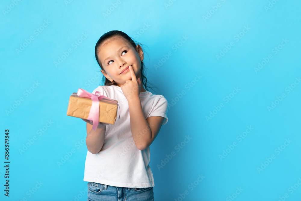 Happy girl holding gift box at turquoise studio Happy girl holding gift box at turquoise studio