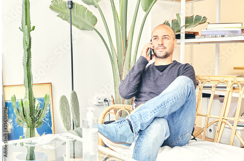 Caucasian man in jeans sitting on a couch talking on the phone photo