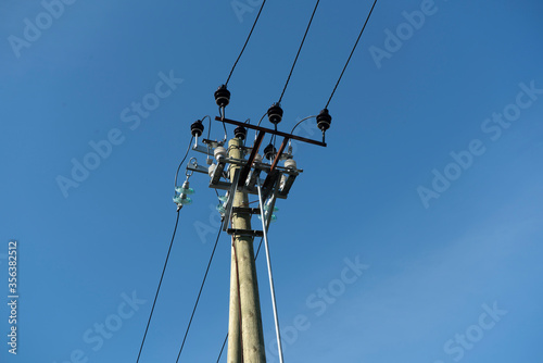 Wooden electric pole with wires. Pillar against the blue sky.