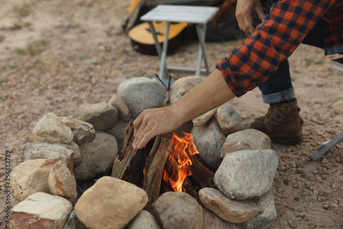 Side view of man preparing the fire of the camp photo