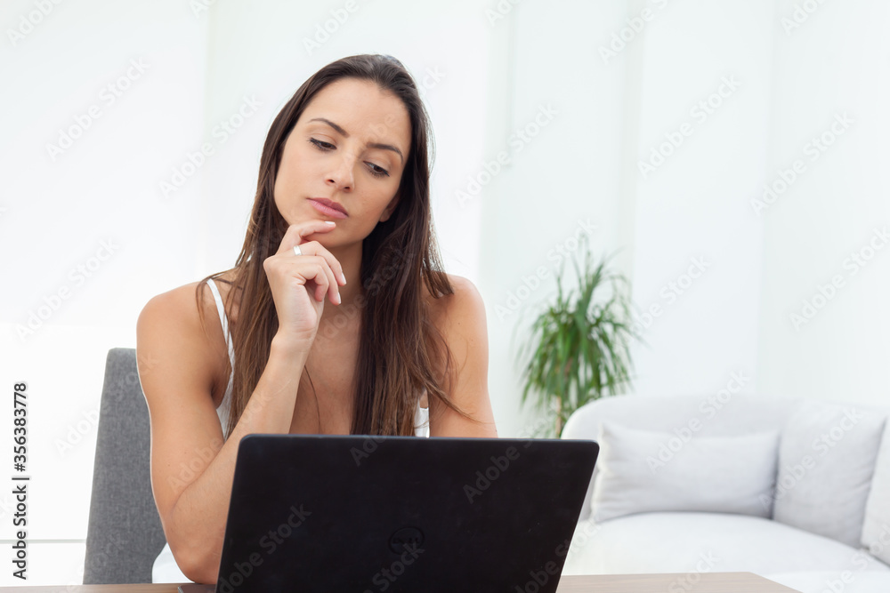 Young woman reading a message on laptop Young woman reading a message on laptop