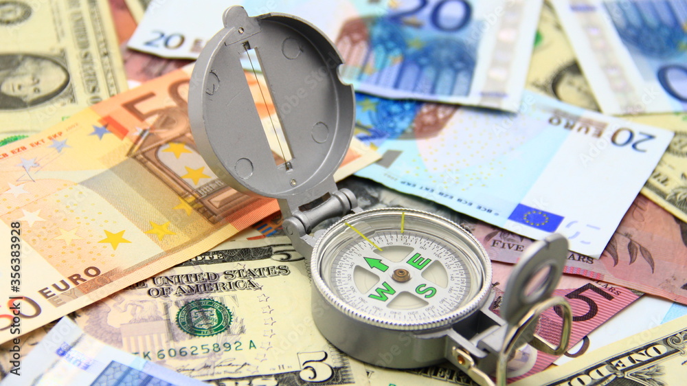Small compass on international paper money. Where to move? Direction in economy to be found. Small compass on international paper money. Where to move? Direction in economy to be found.